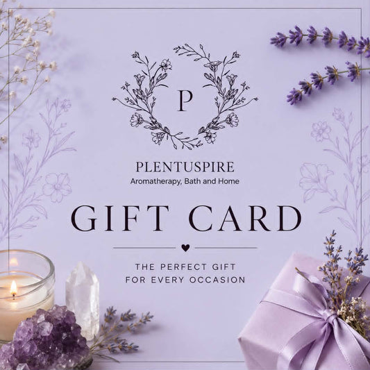 A lavender gift card with elegant black typography reading 'PLENTUSPIRE Aromatherapy, Bath and Home GIFT CARD THE PERFECT GIFT FOR EVERY OCCASION,' surrounded by spa-themed props including a lit candle, purple crystals, dried lavender sprigs, and a lavender gift box.