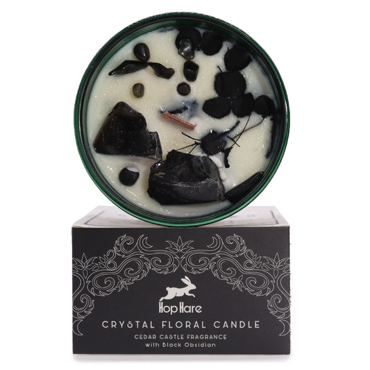 Soy wax candle with black obsidian crystals, dried flowers, wooden wick in dark green jar.