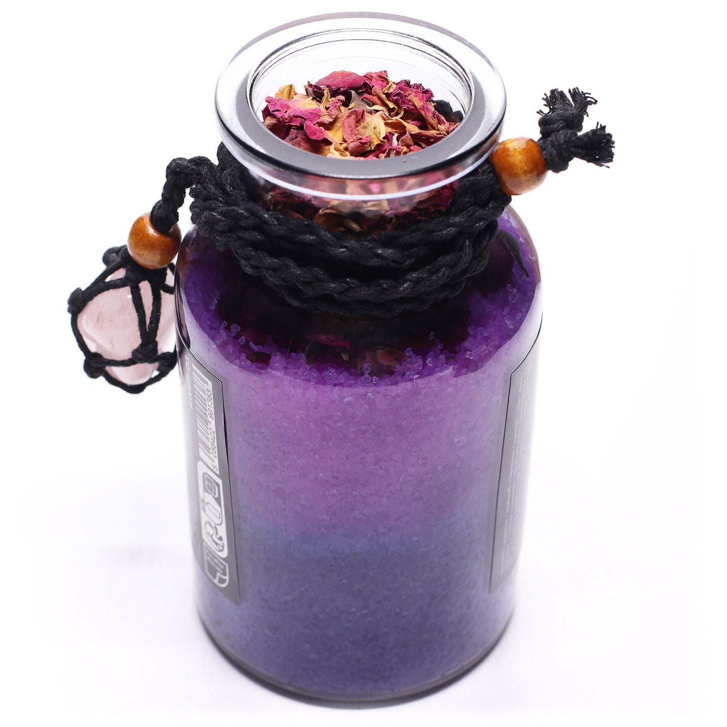 Glass bottle with cork lid off filled with Himalayan bath salts and rose petals infused with Rose Geranium and Grapefruit essential oils with a Rose Quartz crystal amulet from above