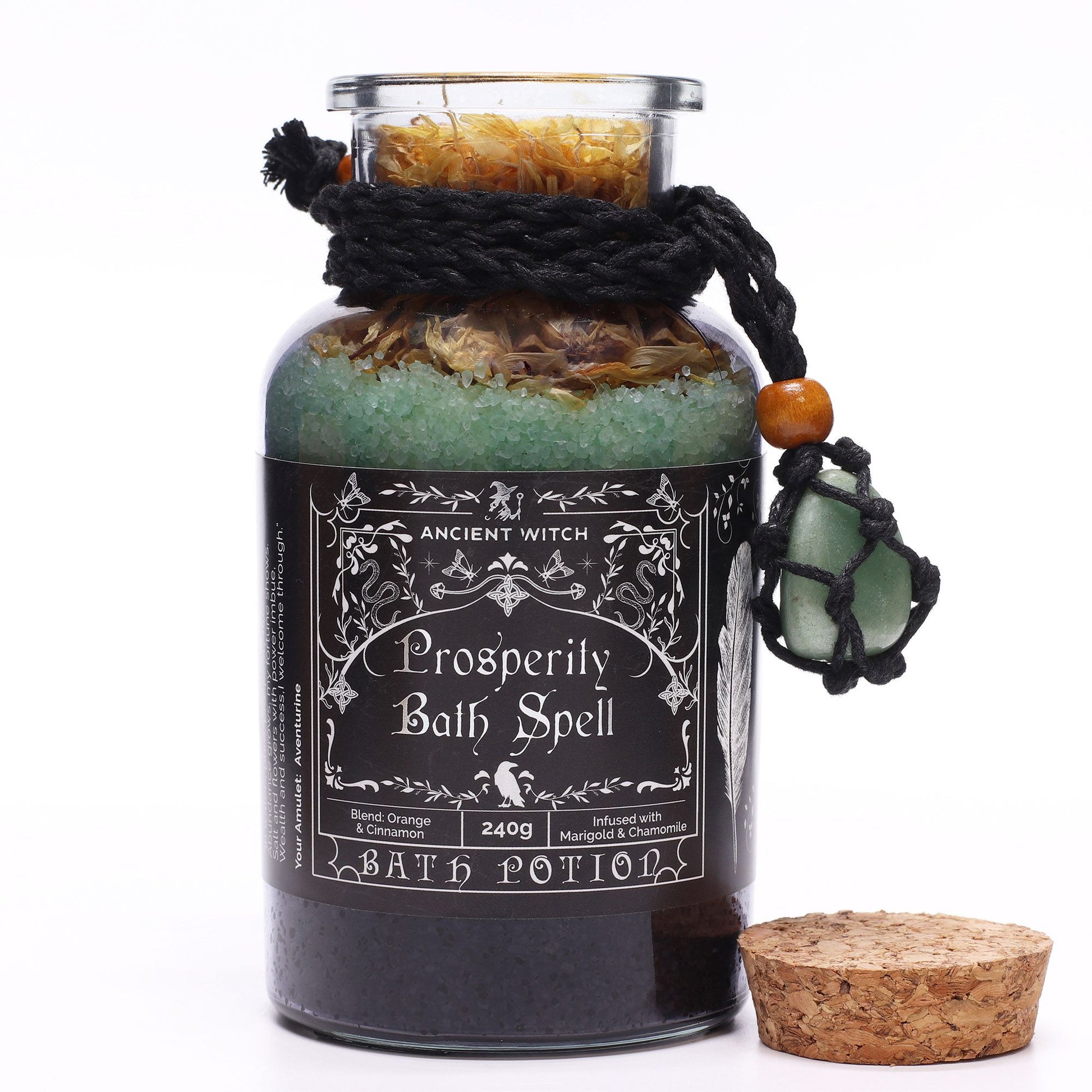 Glass bottle with cork lid off filled with Himalayan bath salts, marigold and chamomile botanicals with Orange and Cinnamon essential oils and a green Aventurine crystal amulet