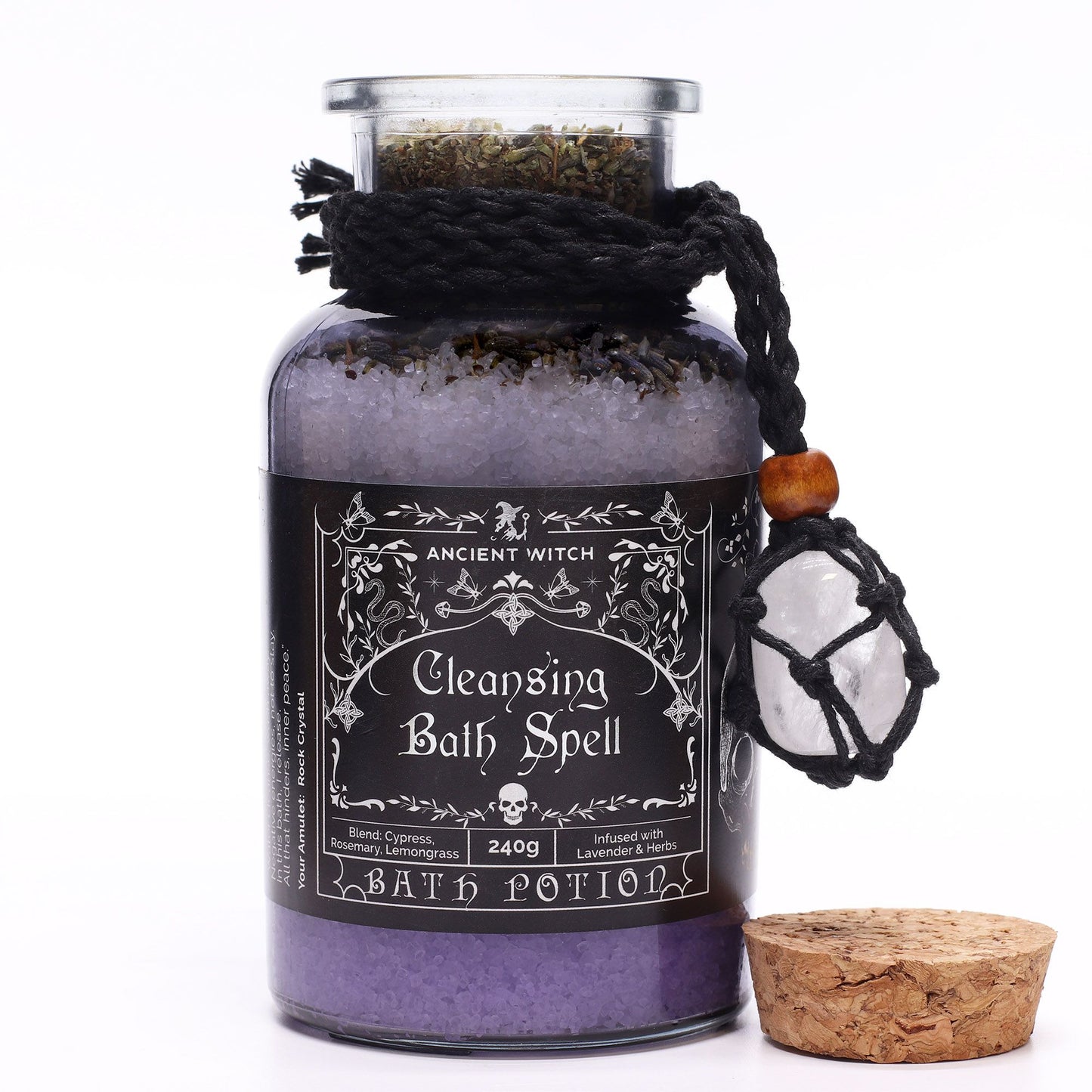 Glass bottle with cork lid off filled with Himalayan bath salts, lavender and botanicals infused with Cypress, Rosemary and Lemongrass essential oils with a Clear Quartz crystal amulet